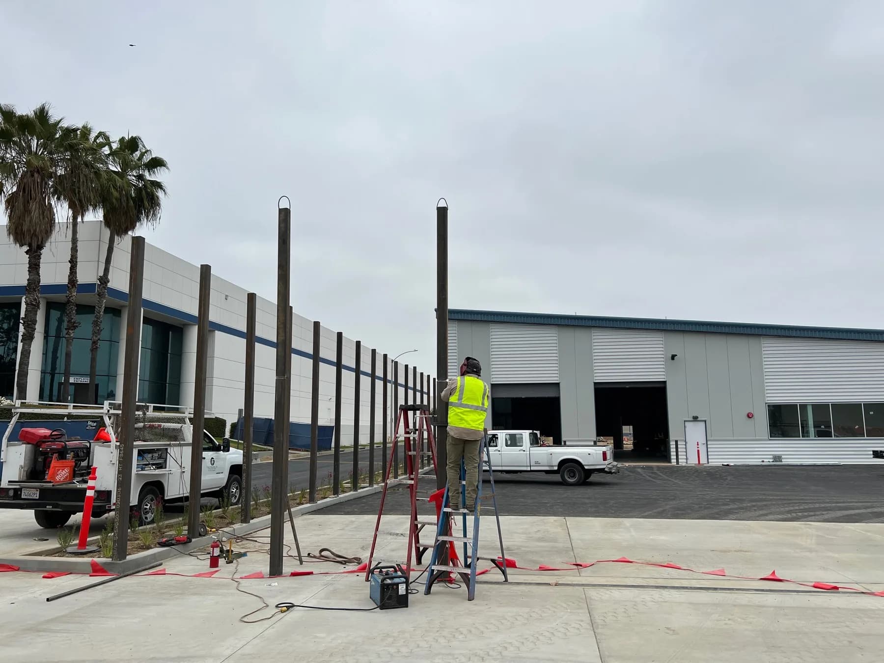 Fence installer setting black commercial picket fencing beside a large building