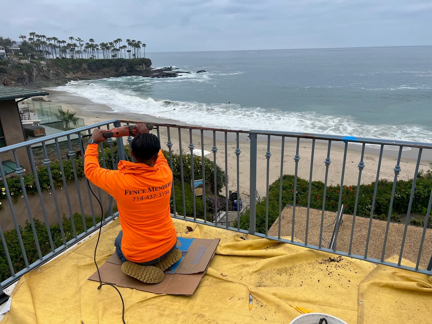 Fence Menders technician using a power tool while repairing a balcony guardrail