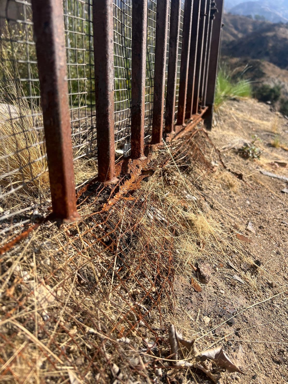 Rust at the base of an iron perimeter fence before repair