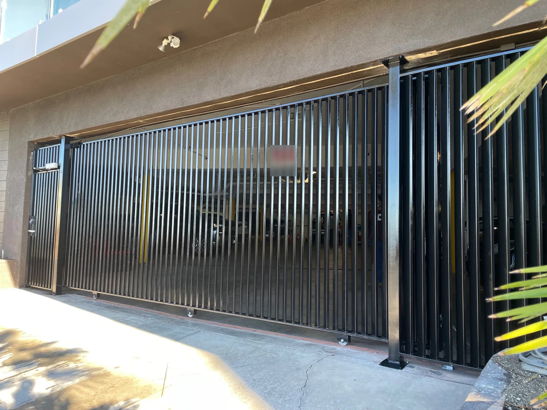 Black sliding picket gate across a multifamily covered parking entrance