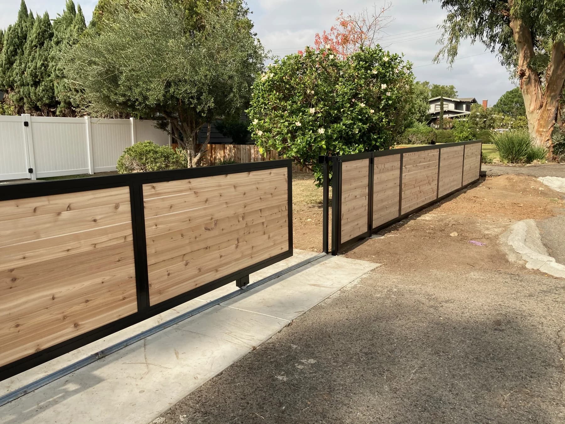 Modern wood-infill sliding vehicle gate with matching privacy fence panels
