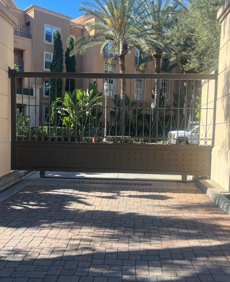 Brown decorative sliding vehicle gate at a masonry property entrance