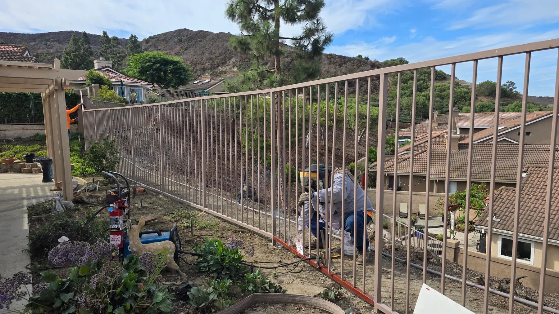 Long metal guardrail with a worker and repair equipment along a landscaped slope