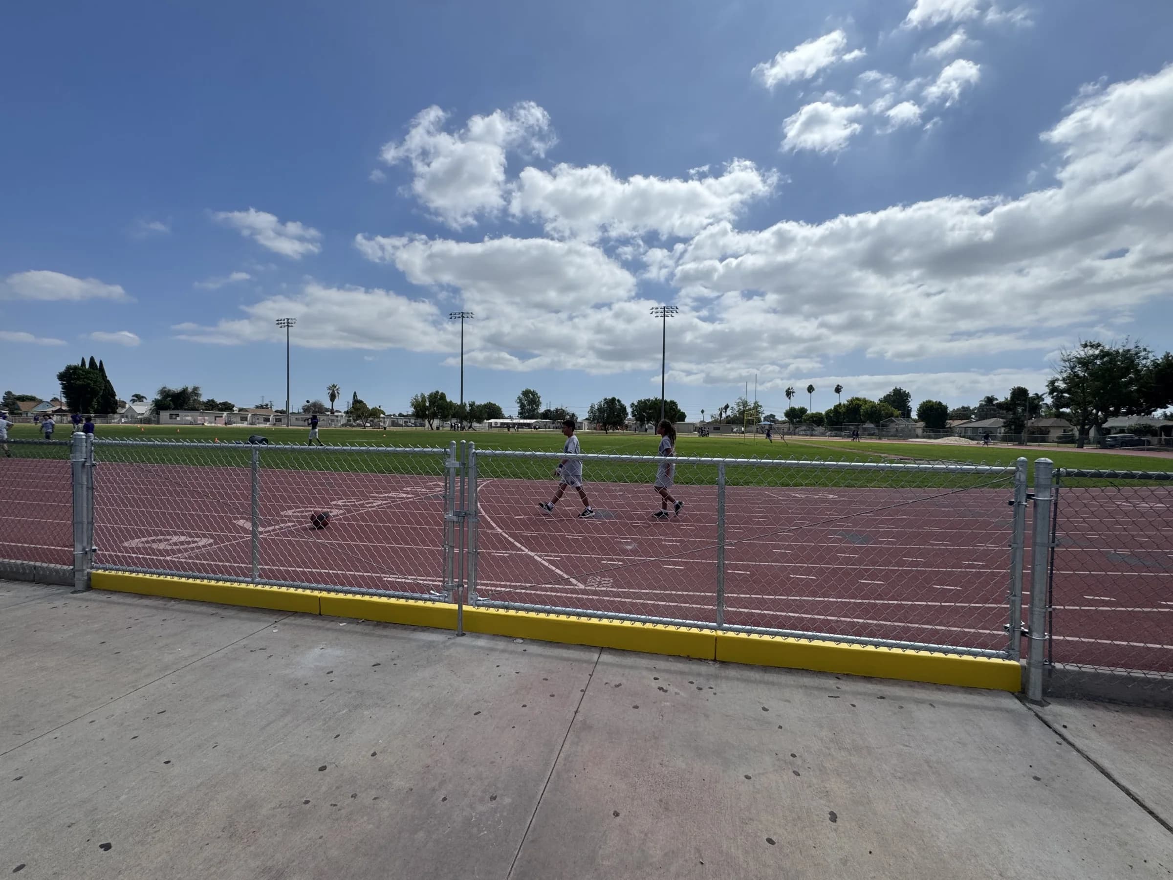 Finished chain-link perimeter and swing gates around a school running track