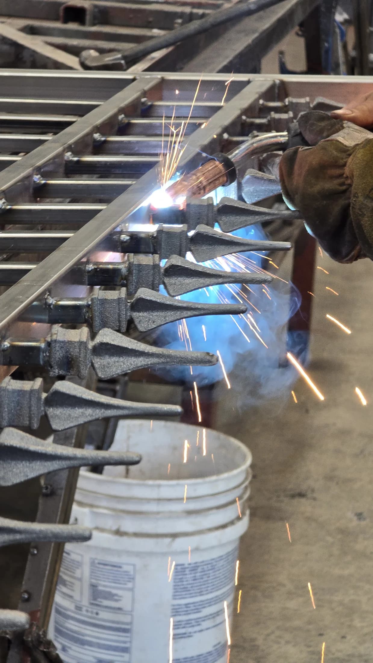 Fence Menders welder fabricating a wrought-iron perimeter section in the Santa Ana shop
