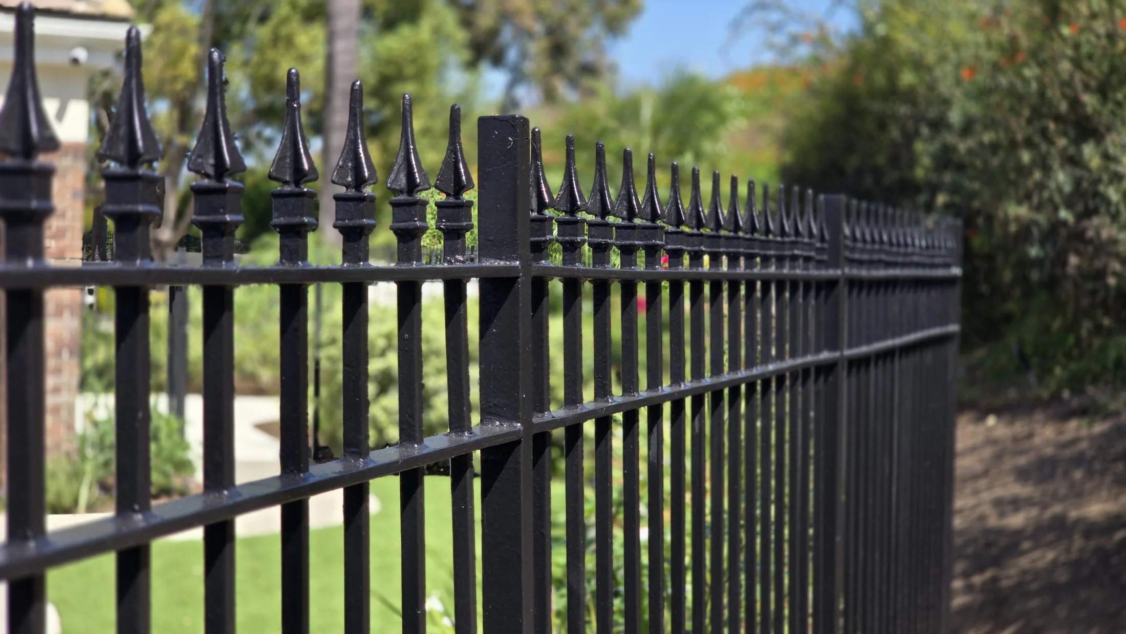 Finished black wrought-iron perimeter fence following a landscaped Orange County community slope